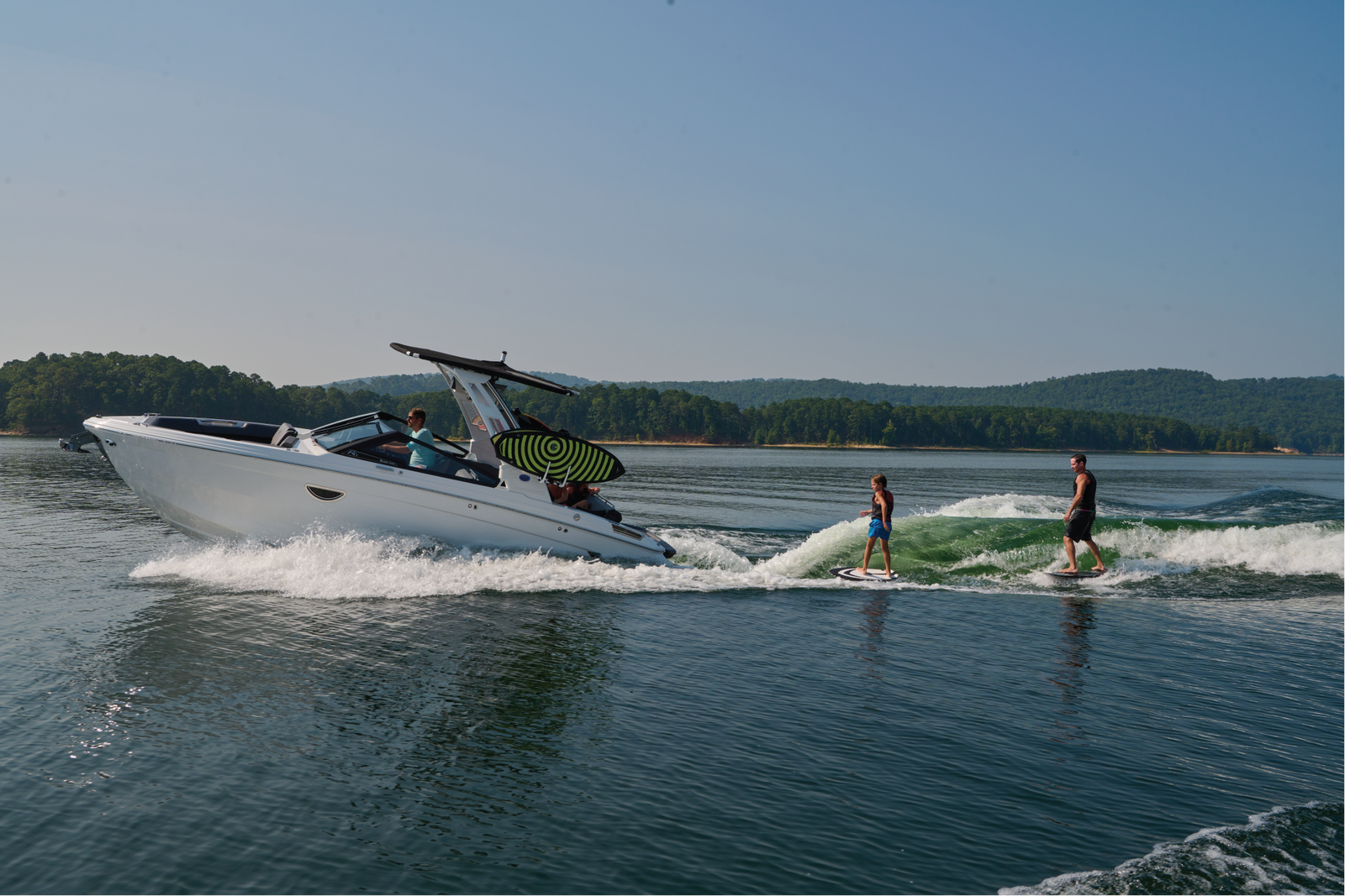 White Cobalt boat towing two wakesurfers across a lake