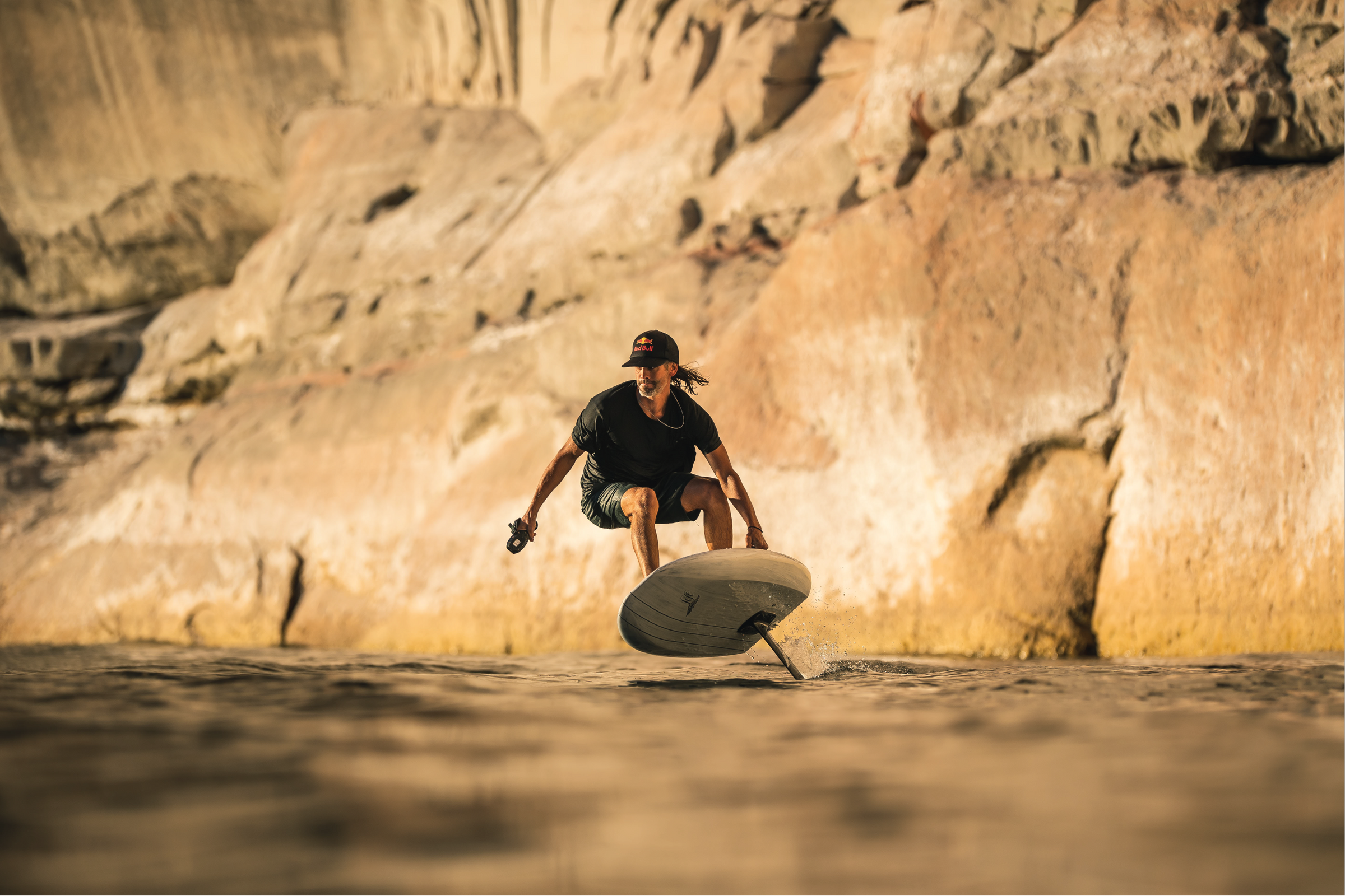 Rider crouching low while riding a Lift e-foil on calm water