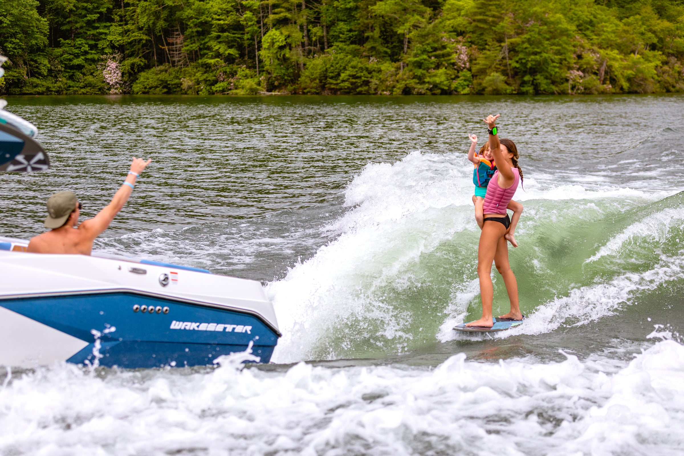 Wakesurfer being cheered on from a boat while riding the wave