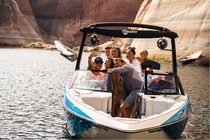 Group of friends relaxing on a Malibu boat in a red-rock canyon lake