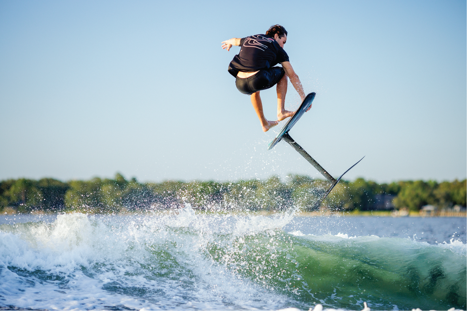 Wakefoil rider catching air above the wake on a sunny lake