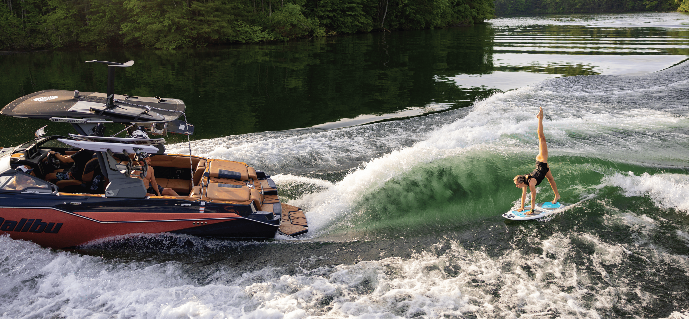 Wakesurfer carving the wave behind a wakeboard boat on a calm lake
