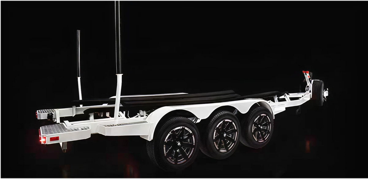 White triple-axle boat trailer with black wheels on a dark background