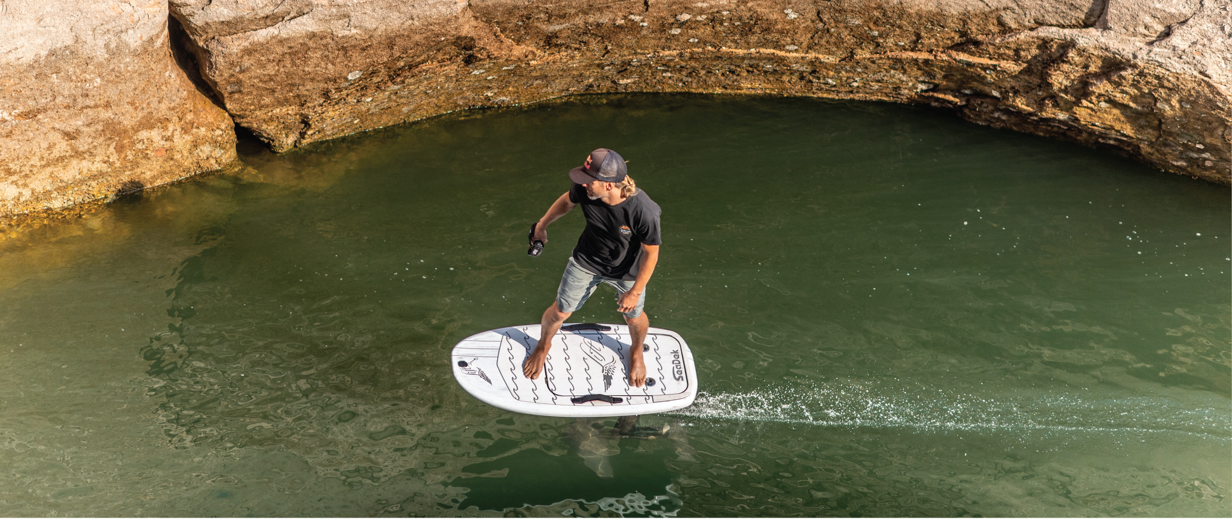 Rider e-foiling across calm water in a rocky canyon