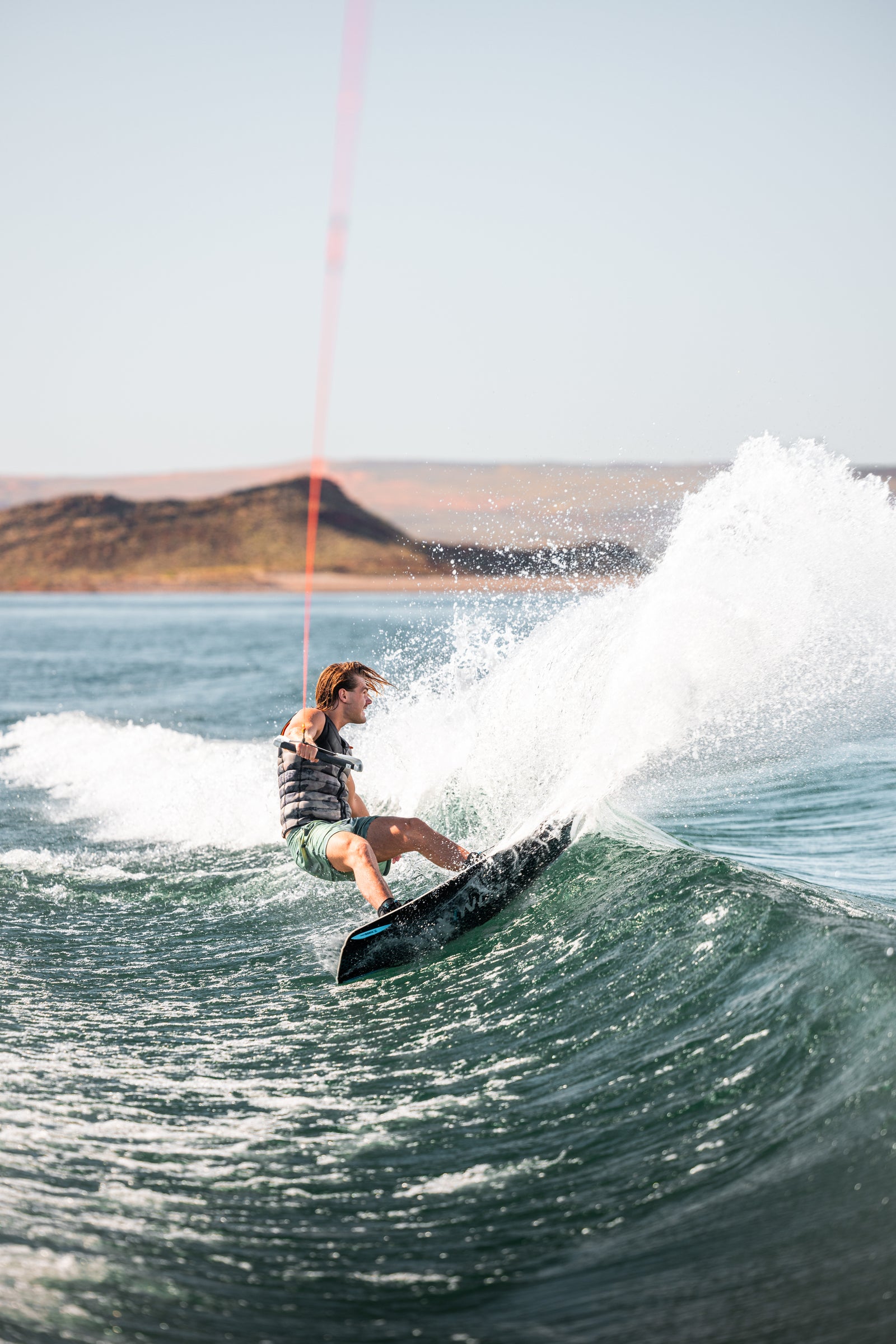 Woman wakesurfing carving down the face of a wave