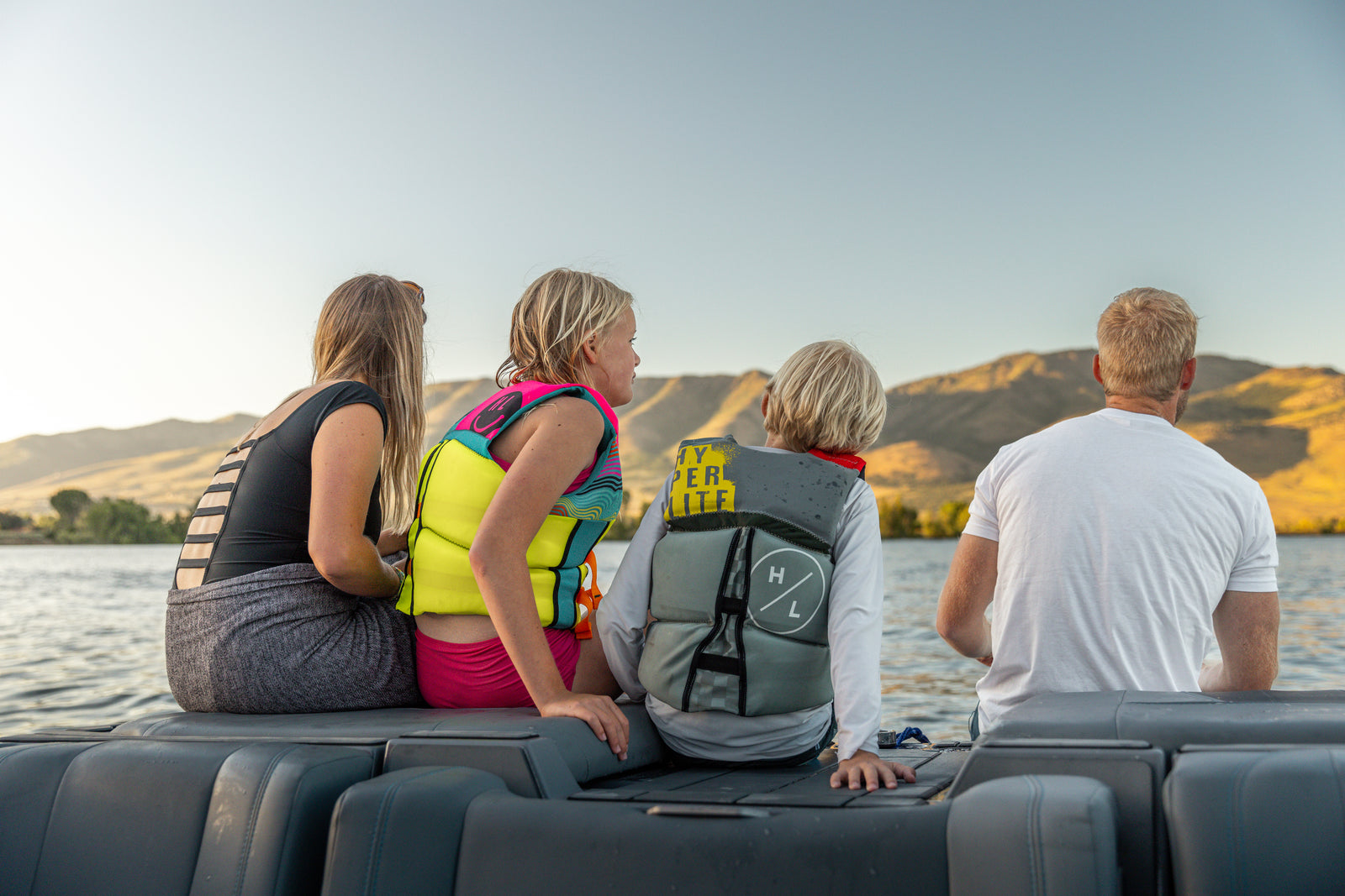Family of four sitting on a boat looking out over a lake toward desert mountains